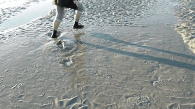 Person playfully bouncing on wet beach sand