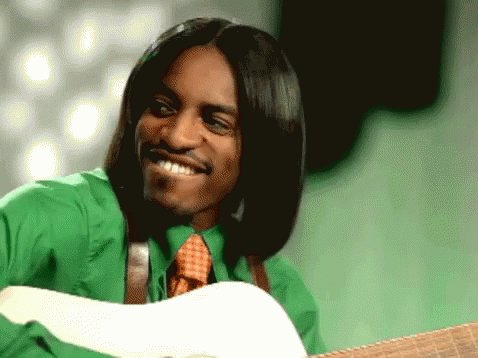 A GIF of musician André 3000 wearing a green shirt and play