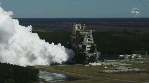 The core stage of NASA's Space Launch System Moon rocket powers up for an eight minute test with huge plumes of water vapor rising to the sky. 