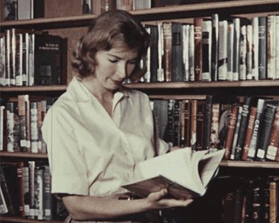 Gif de una mujer con ropa vintage hojeando un libro en una b
