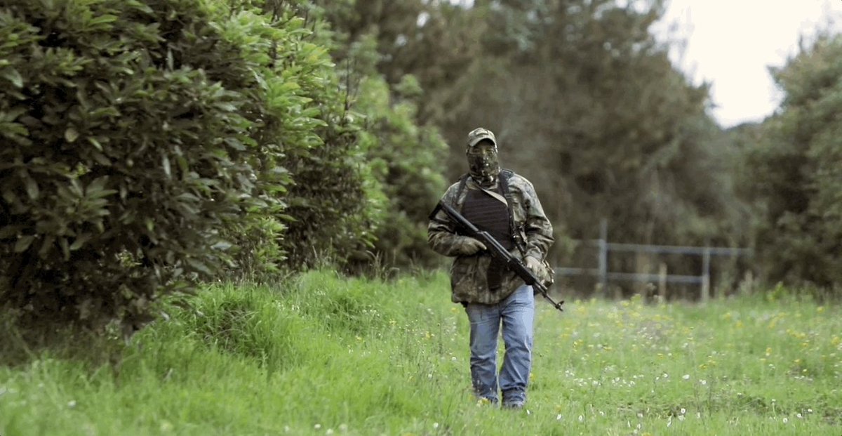 Gif showing a man walking with a large gun and protective ge