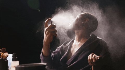 A Black man sits in front of a counter with makeup and luxur