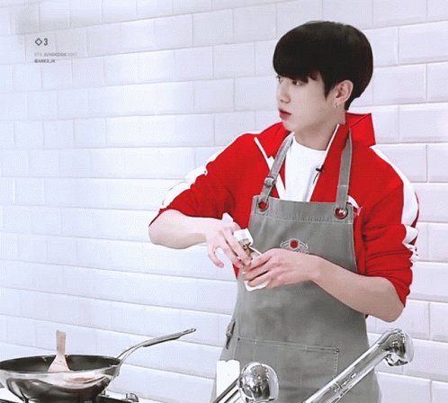 Young cook adding a pinch of salt to food 